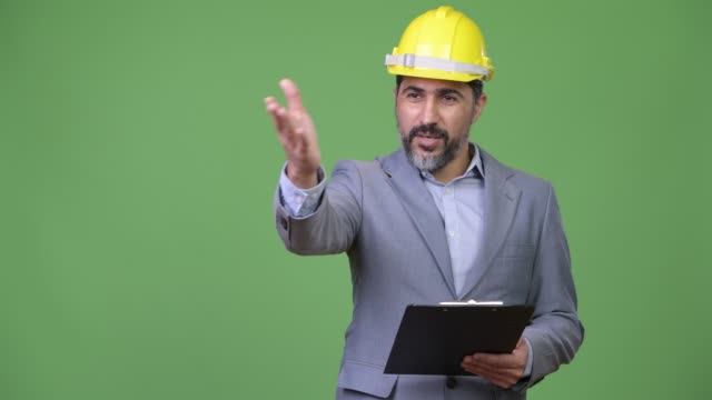 Handsome-Persian-bearded-businessman-as-engineer-directing-with-clipboard