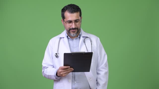 Handsome-Persian-bearded-man-doctor-thinking-while-holding-clipboard
