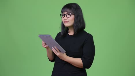 Schöne-asiatische-geschäftsfrau-denken-bei-der-Verwendung-von-digital-Tablette
