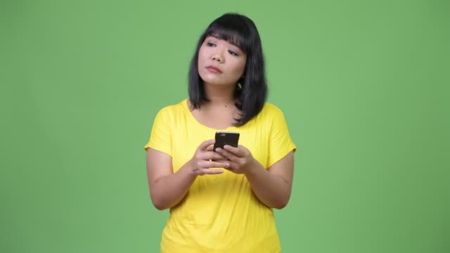 Schöne-asiatische-Frau-denken-bei-der-Verwendung-von-Telefon