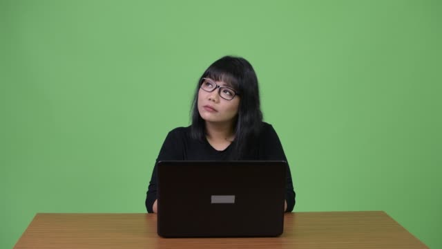 Hermosa-empresaria-asiática-pensando-durante-el-uso-del-ordenador-portátil