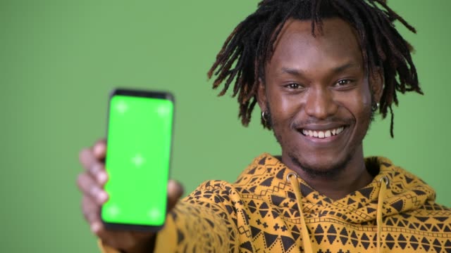 Glücklich-schönen-jungen-afrikanischen-Mann-lächelnd-beim-Telefon-zeigen