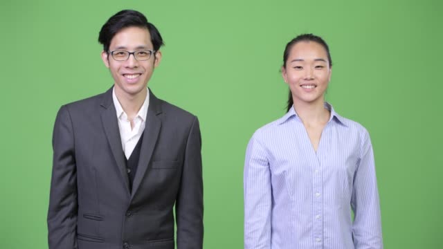Pareja-de-negocios-asiática-joven-apuntando-a-cámara-juntos