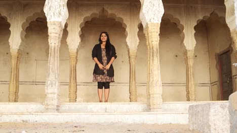 Mujer-India-saluda-namaste-da-la-bienvenida-a-invita-a-alegría-caliente-templo-antiguo-hindú-arquitectura-tradicional-pelo-negro-sonrisa-feliz-invitado-copia-estática-interior-casa-espacio-ancho-disparo-bloqueo-marco