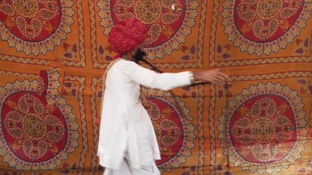 Handheld-Rajasthani-älteren-männlichen-Anzeige-seiner-riesigen-Schnurrbart-und-tanzen-vor-einem-bunten-Stoff-Zelt