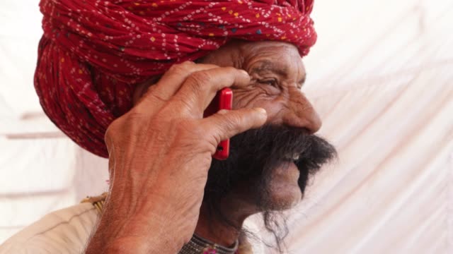 Mano-hombre-mayor-de-Rajasthani-en-una-conversación-móvil-del-teléfono-celular-inteligente