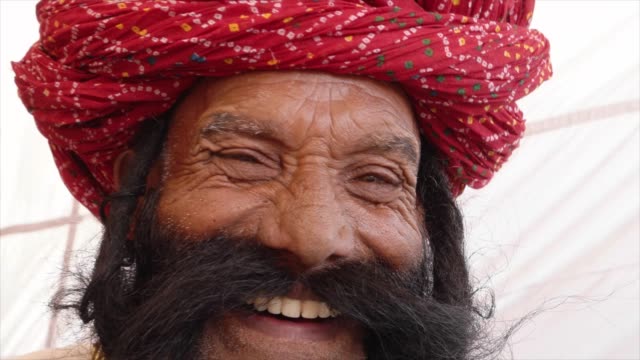 Close-up-Smiling-man-from-Rajasthan-salutes-with-big-moustache-wearing-a-red-turban-and-tradition-dress