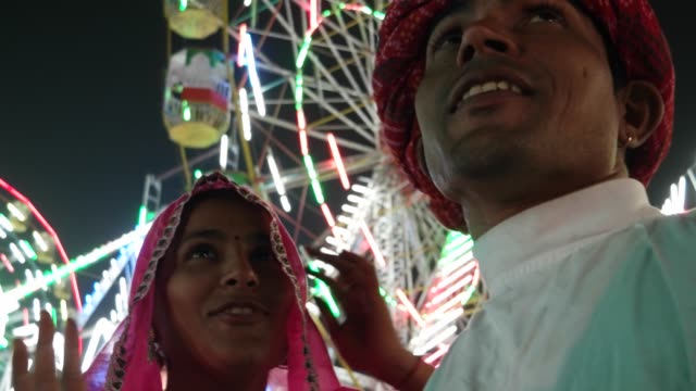 Pareja-tradicional-indio-hablando-en-sari-rosa-y-turbante-rojo-en-Pushkar-Mela,-un-carnaval-de-Rajasthán,-la-India