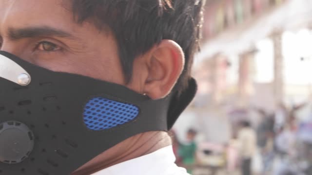 Hombre-indio-con-una-máscara-de-contaminación-en-un-festival-de-Mela-ocupado-en-Rajasthan,-India