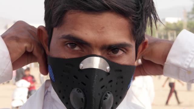 Indischer-Mann-trägt-seine-Maske-Verschmutzung-und-dreht-sich-auf-einem-belebten-Mela-Festival-In-Rajasthan,-Indien