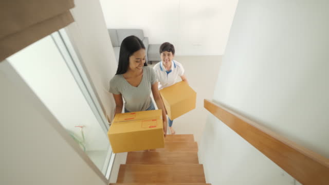 Happy-asian-women-LGBT-lesbian-couple-holding-boxes-entering-new-modern-house