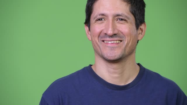 Glücklicher-Hispanic-Mann-denken-vor-grünem-Hintergrund