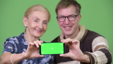 Glückliche-Großmutter-und-Enkel-zeigt-Handy-zusammen
