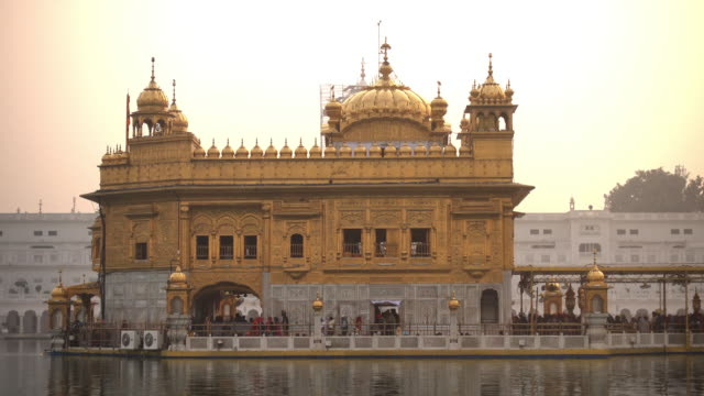 Video-de-peregrinos-sijs-en-el-templo-de-oro-de-puesta-de-sol-durante-el-día-de-la-celebración-en-diciembre-en-Amritsar,-Punjab,-India.-Harmandir-Sahib-es-el-sitio-más-sagrado-del-peregrino-para-los-Sikhs.