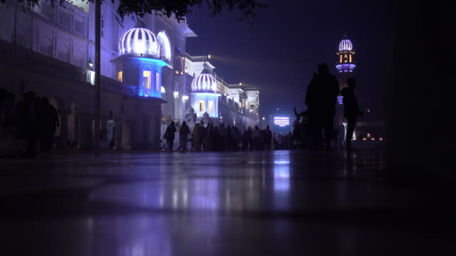 Video-de-peregrinos-sijs-en-el-templo-de-oro-en-la-noche-durante-la-celebración-del-día-de-diciembre-en-Amritsar,-Punjab,-India.-Harmandir-Sahib-es-el-sitio-más-sagrado-del-peregrino-para-los-Sikhs.