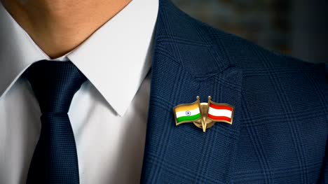Businessman-Walking-Towards-Camera-With-Friend-Country-Flags-Pin-India---Austria