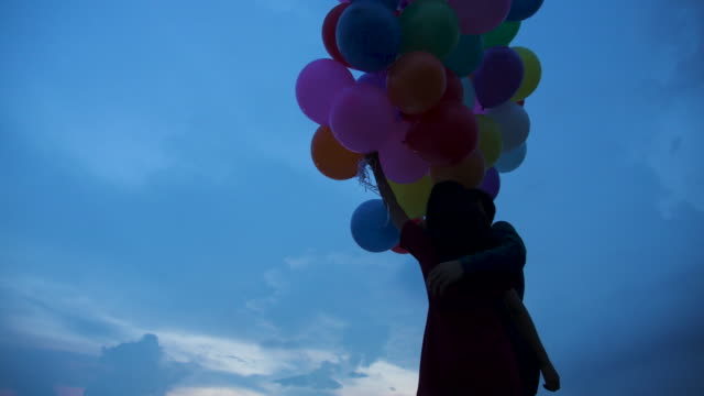 Young-couple-people-holding-balloon-with-sunset-background-in-slow-motion.