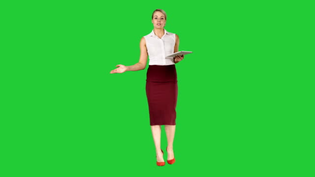 Mujer-de-negocios-con-tablet-caminando-y-hablando-con-la-cámara-en-una-pantalla-verde-Chroma-Key