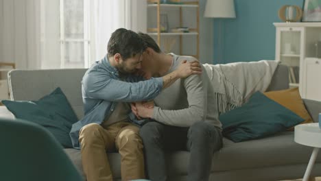 Sad-Queer-Drama-Concept.-Boyfriend-is-Unhappy-and-Depressed-About-Something.-His-Gay-Friend-is-Comforting-Him,-Holding-His-Hands.-Miserable-Man-Puts-His-Head-on-a-Shoulder-and-Cries.