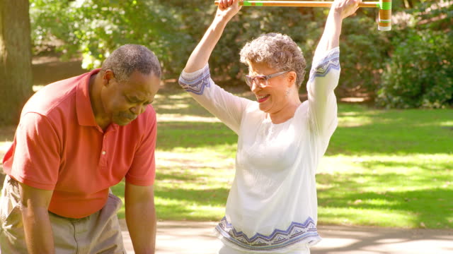 Mujer-madura-negro-celebra-mientras-juegan-al-Croquet-en-un-parque