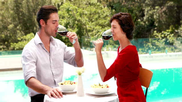 Smiling-couple-drinking-wine-poolside