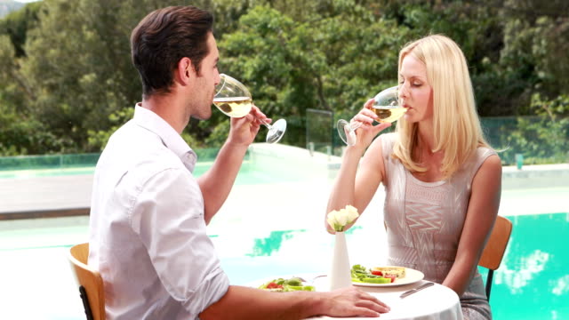 Smiling-couple-drinking-wine-poolside