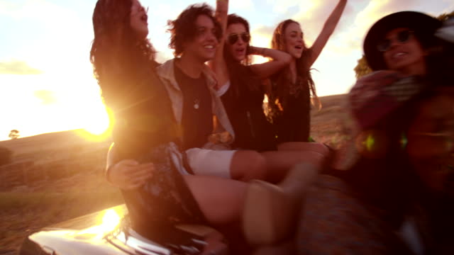 Teenager-friends-embracing-joyfully-on-their-road-trip-at-sunset