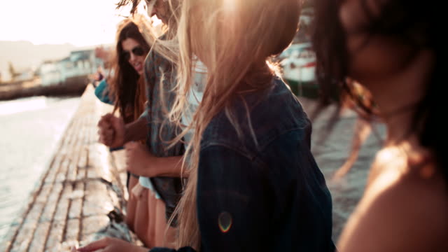 Adolescente-ESTILO-hipster-amigos-bailando-en-el-Muelle-al-anochecer