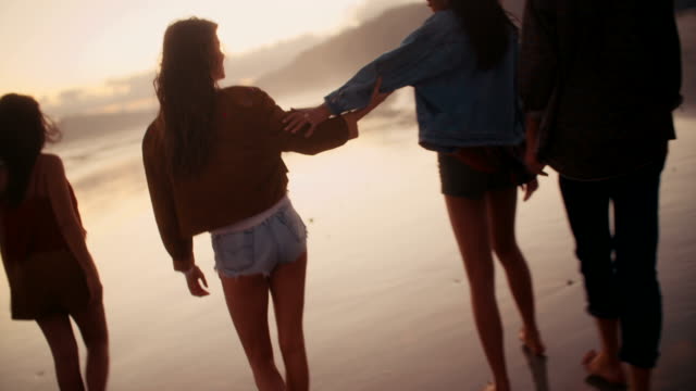 Teen-amigos-disfrutando-de-un-paseo-en-la-playa-en-el-atardecer