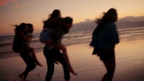 Hipster-friends-doing-funny-piggyback-rides-on-beach