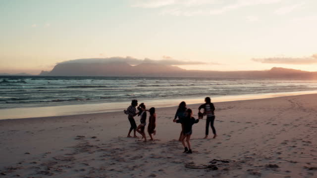 Silueta-de-Teen-amigos-bailando-en-la-playa-al-anochecer