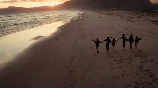 Junge-Freunde-genießen-einen-Spaziergang-am-Strand-bei-Sonnenuntergang