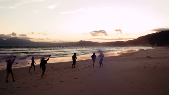 Teenager-friends-celebrating-with-smoke-bombs-on-beach