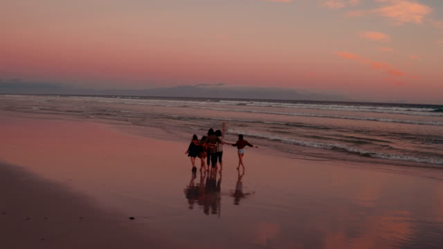 Teen-friends-enjoying-a-walk-at-beach-on-sunset