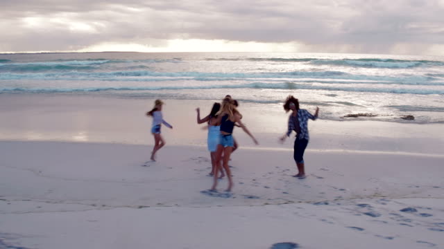 Teen-amigos-bailando-en-la-playa-al-anochecer