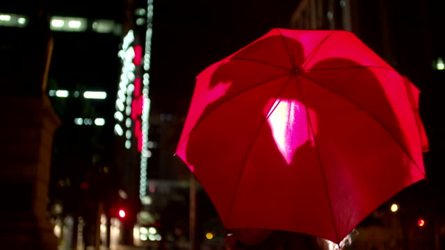 Paar-küssen-hinter-einem-roten-Regenschirm-in-der-Stadt