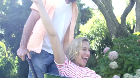 Happy-couple-playing-with-a-wheelbarrow-in-the-garden