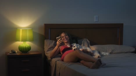 Mujer-y-perro-en-la-cama-tomando-Selfie-con-teléfono-en-la-noche