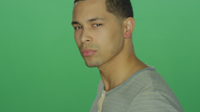 Young-African-American-man-looking-intensely-at-the-camera,-on-a-green-screen-studio-background