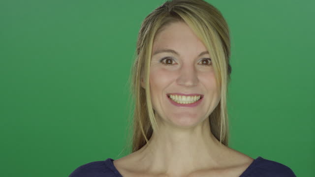 Beautiful-woman-smiling-big,-on-a-green-screen-studio-background