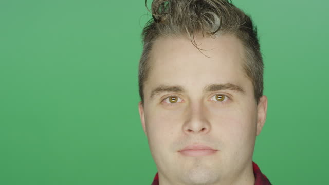 Young-man-staring-ahead,-on-a-green-screen-studio-background