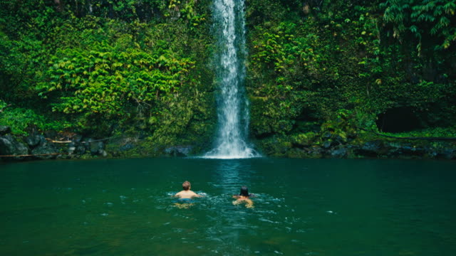 Couple-Swimming-to-Waterfall