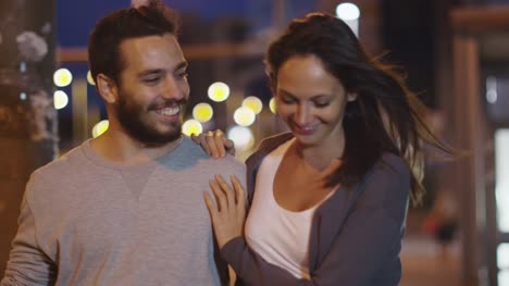 Atractiva-pareja-feliz-caminando-por-las-calles-de-la-ciudad-de-noche