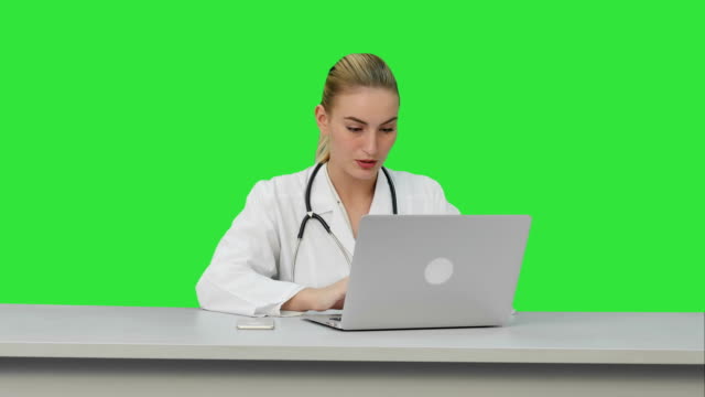Seriouse-Ärztin-arbeitet-auf-ihrem-Laptop-auf-einem-Green-Screen,-Chroma-Key