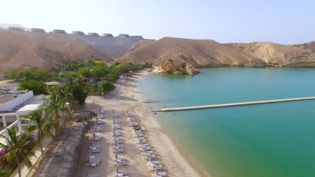 Aerial-view-of-Muscat-bay,-dive-resort,-day-trip-and-relaxing-area,-crystal-clear-water-of-Indian-Ocean,-beach-and-blue-lagoon,-Oman,-sultanate-on-Arabian-Peninsula,-4k-UHD