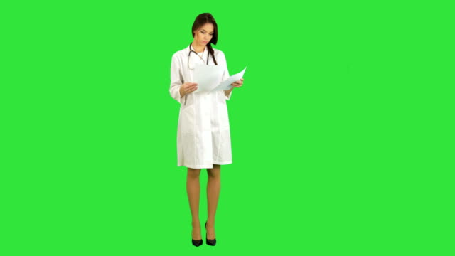 Young-nurse-reading-patient-medical-history-forms-on-a-Green-Screen,-Chroma-Key