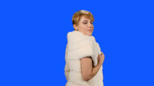 Beautiful-model-in-fur-cape-poses-for-camera-at-blue-background