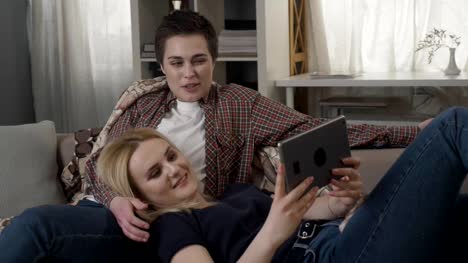 Lesbian-couple-is-resting-on-the-couch,-and-having-video-conversation-with-friend,-showing-sign-no-by-shaking-head-60-fps