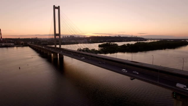 Brücke-mit-Trafic-über-den-Fluss-bei-Sonnenuntergang-Luftbild-Drohne-Filmmaterial