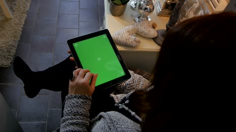 Frau-auf-dem-Boden-sitzend-und-mit-vertikalen-Tablet-Computer-mit-Greenscreen.-Schuss-von-Frauenhand-mit-Pad-hautnah.-Technologie-und-Internet-Konzept